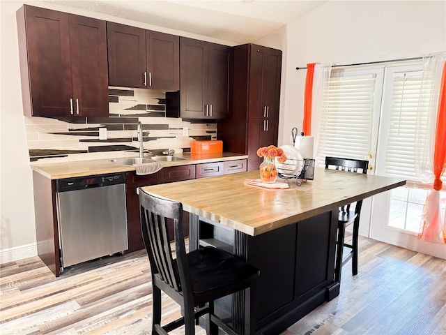 kitchen with sink, tasteful backsplash, stainless steel dishwasher, light hardwood / wood-style floors, and a breakfast bar