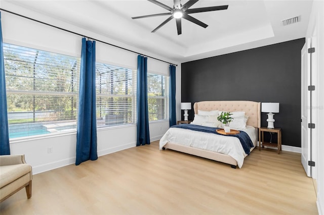 bedroom featuring a raised ceiling, ceiling fan, and light hardwood / wood-style floors