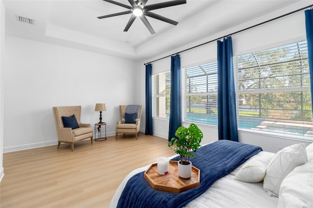 bedroom featuring hardwood / wood-style floors, ceiling fan, and a tray ceiling