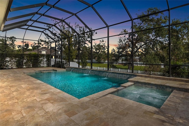 pool at dusk featuring an in ground hot tub, pool water feature, a patio, and a lanai