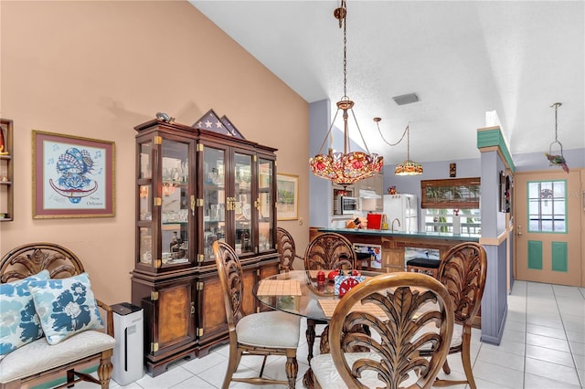 dining space featuring light tile patterned floors, a chandelier, and high vaulted ceiling