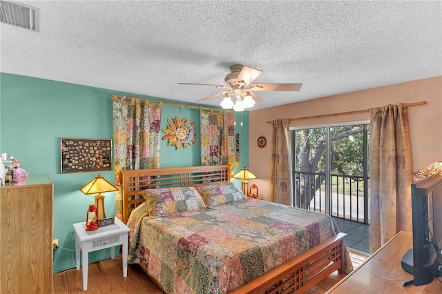 bedroom with access to outside, ceiling fan, wood-type flooring, and a textured ceiling