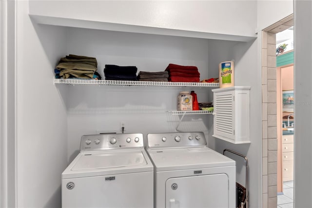 laundry room with washer and clothes dryer, light tile patterned floors, and sink