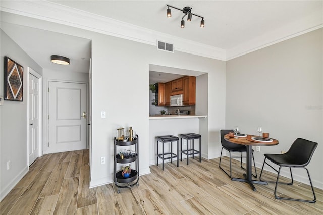 dining area featuring light hardwood / wood-style flooring and crown molding