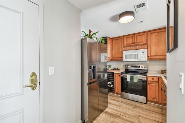 kitchen featuring backsplash, stainless steel appliances, and light hardwood / wood-style floors