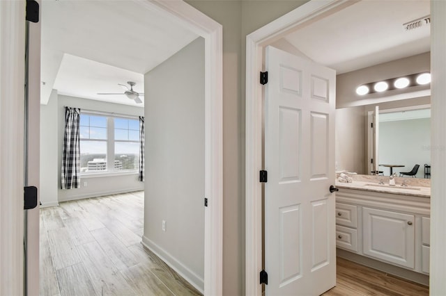 bathroom with hardwood / wood-style floors, ceiling fan, and vanity