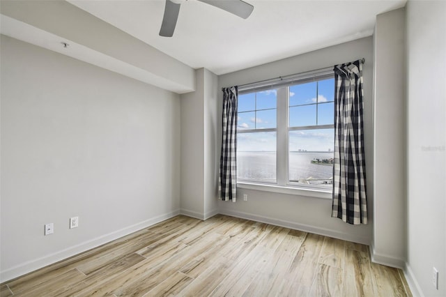 unfurnished room with light wood-type flooring, a water view, a wealth of natural light, and ceiling fan