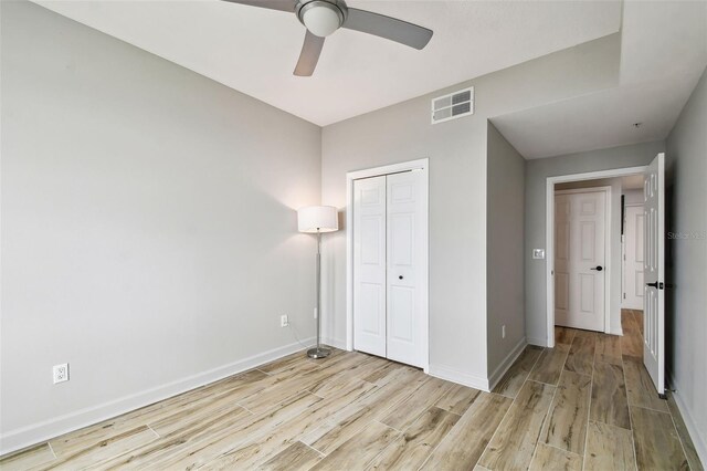 unfurnished bedroom with ceiling fan, a closet, and light hardwood / wood-style flooring