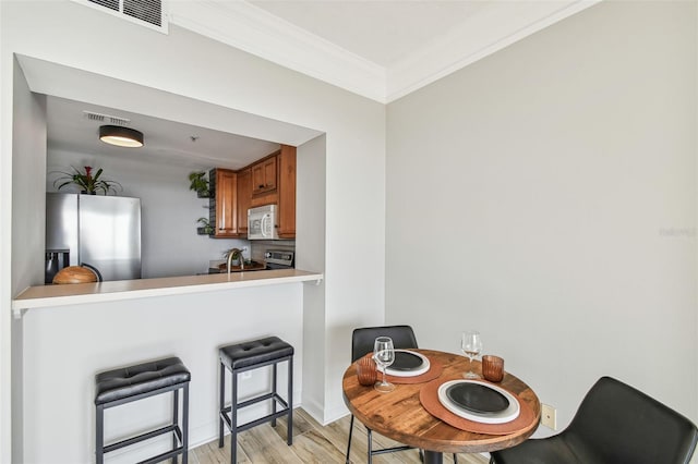 dining space with light hardwood / wood-style floors and crown molding