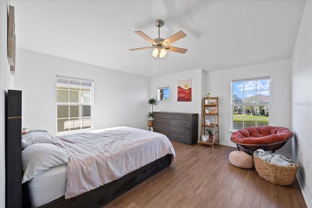 bedroom with multiple windows, ceiling fan, and dark wood-type flooring