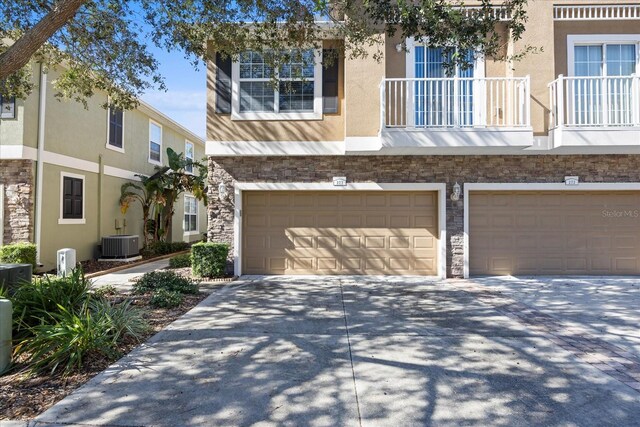 view of property with a garage, a balcony, and central AC