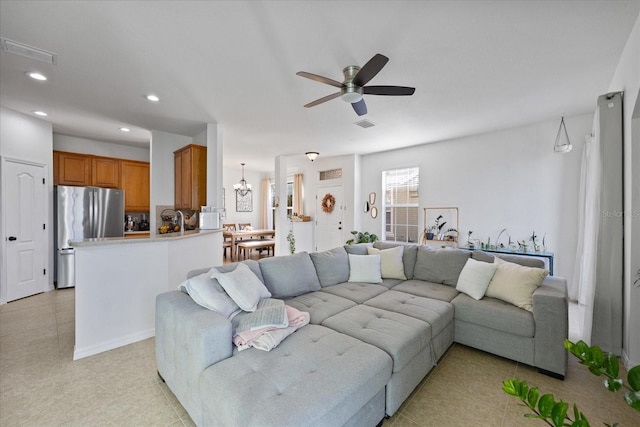 tiled living room with ceiling fan with notable chandelier