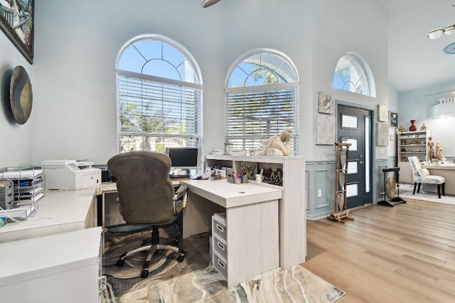 office featuring a towering ceiling and light hardwood / wood-style flooring