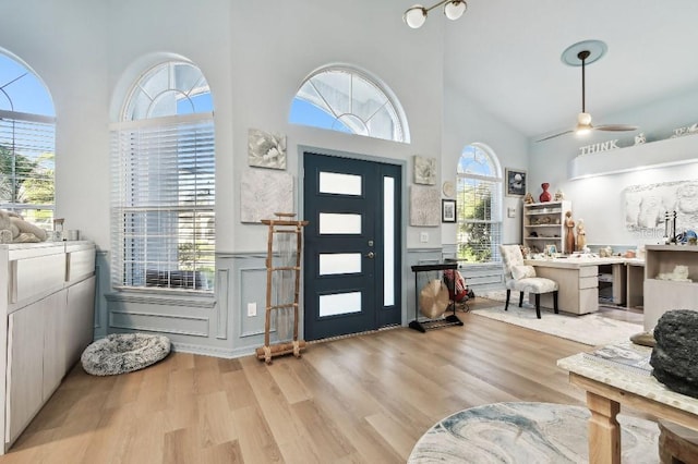 entrance foyer featuring ceiling fan, light wood-type flooring, and a towering ceiling