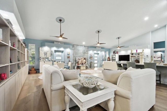 living room with ceiling fan, lofted ceiling, and light hardwood / wood-style flooring