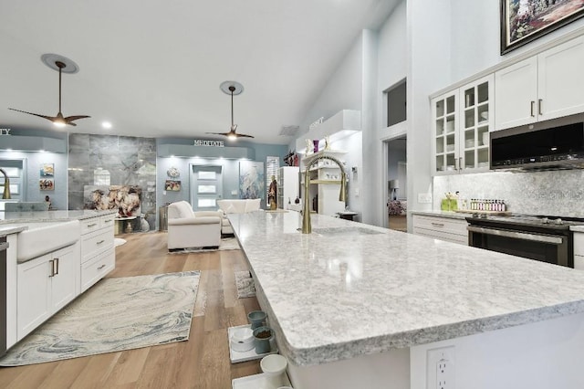 kitchen with appliances with stainless steel finishes, a center island with sink, white cabinetry, and lofted ceiling