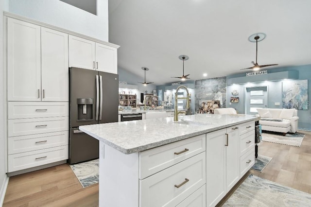 kitchen featuring sink, stainless steel fridge, light wood-type flooring, an island with sink, and white cabinetry