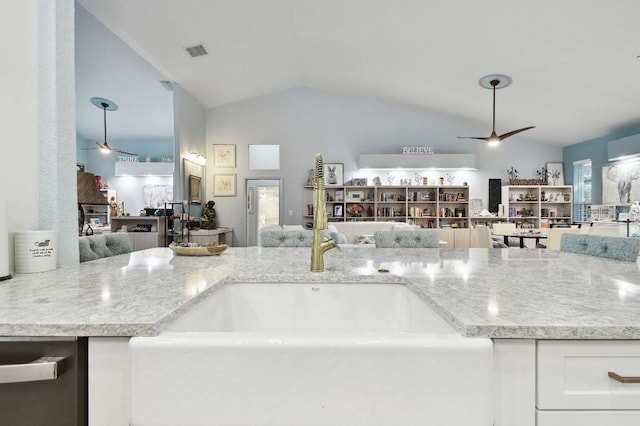 kitchen with dishwasher, white cabinetry, vaulted ceiling, and light stone counters