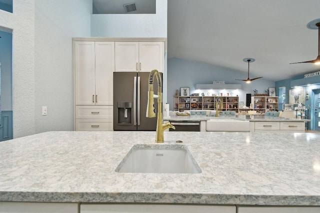 kitchen with sink, white cabinets, vaulted ceiling, and appliances with stainless steel finishes