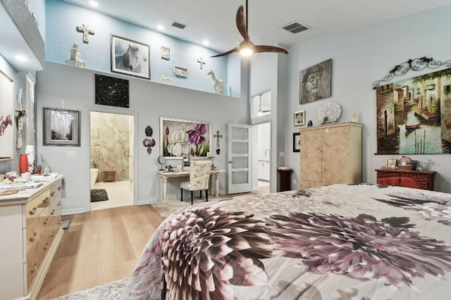 bedroom featuring light wood-type flooring, a towering ceiling, and connected bathroom