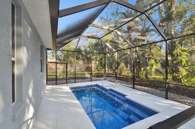 view of swimming pool featuring glass enclosure and a patio