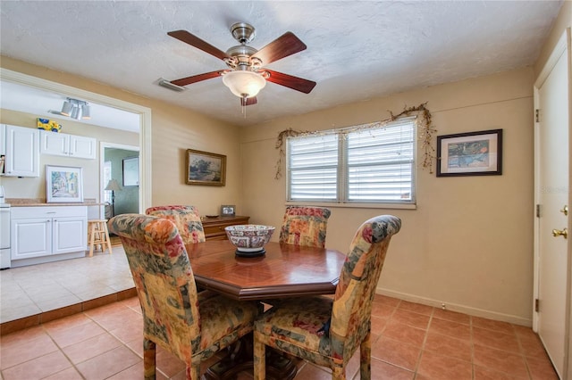 dining area with ceiling fan, light tile patterned floors, and a textured ceiling