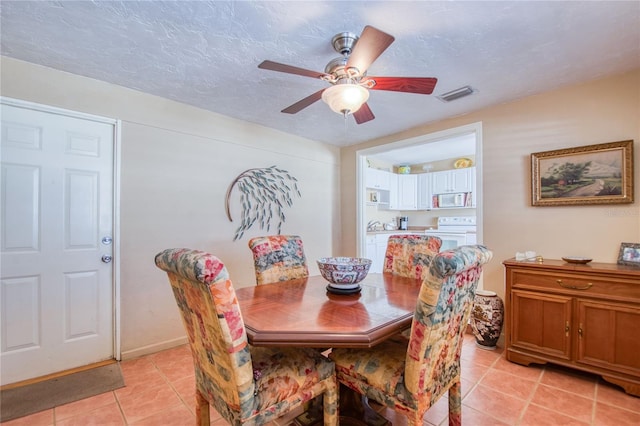 dining space with ceiling fan, light tile patterned floors, and a textured ceiling