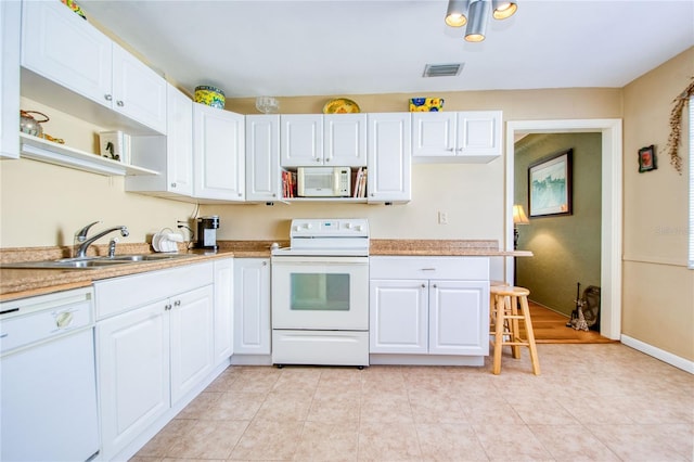 kitchen featuring white cabinets, white appliances, sink, and light tile patterned floors