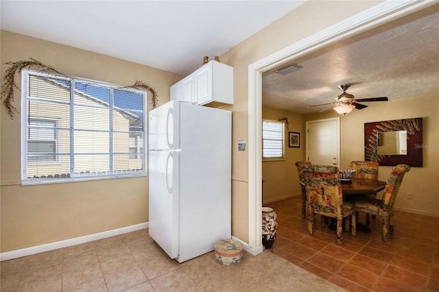 kitchen featuring ceiling fan, white fridge, white cabinetry, and light tile patterned floors