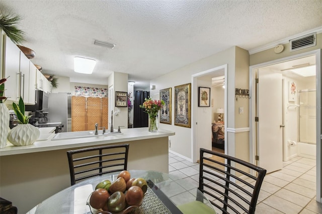 kitchen featuring kitchen peninsula, white cabinets, and light tile patterned flooring