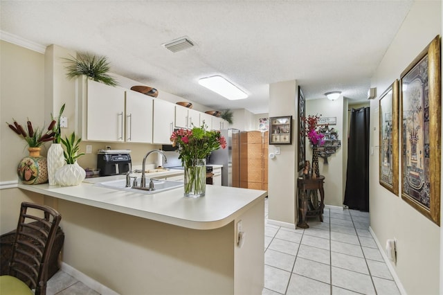 kitchen featuring kitchen peninsula, white cabinets, light tile patterned flooring, and a textured ceiling