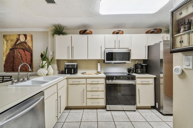 kitchen with light tile patterned floors, a textured ceiling, stainless steel appliances, and sink