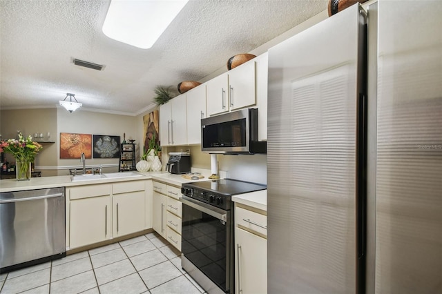 kitchen with light tile patterned floors, a textured ceiling, ornamental molding, appliances with stainless steel finishes, and kitchen peninsula