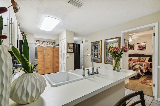 kitchen with ceiling fan, sink, light tile patterned floors, and a textured ceiling