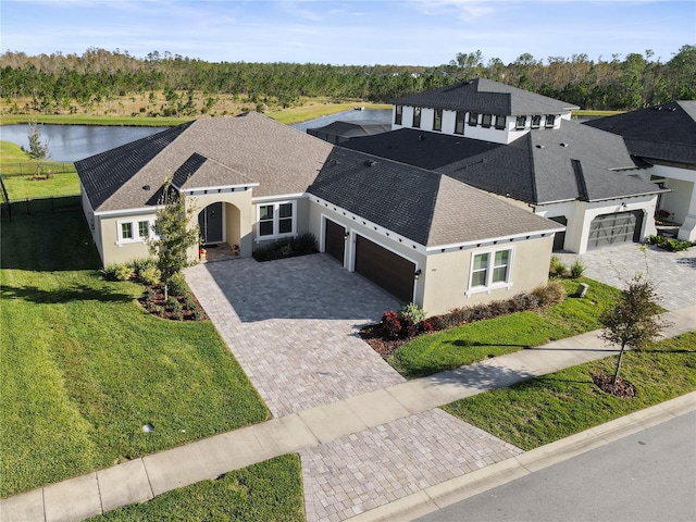 view of front of property featuring a front lawn, decorative driveway, an attached garage, and a shingled roof