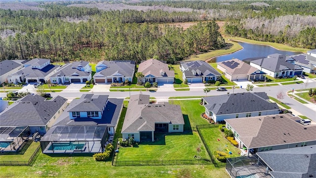 aerial view featuring a forest view, a residential view, and a water view