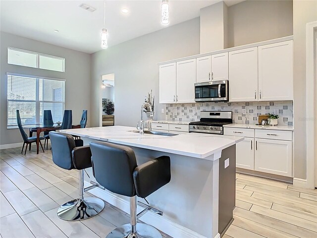 kitchen featuring visible vents, a sink, decorative backsplash, light countertops, and stainless steel appliances