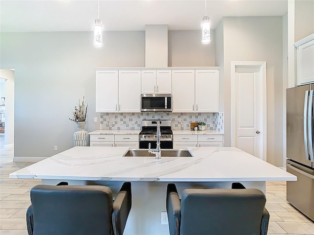 kitchen featuring decorative light fixtures, backsplash, white cabinets, and stainless steel appliances