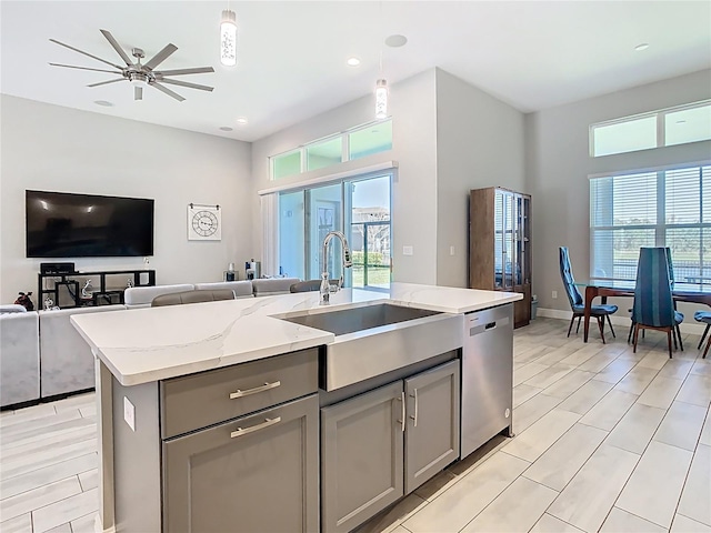 kitchen with a sink, stainless steel dishwasher, open floor plan, and gray cabinets