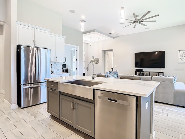 kitchen featuring ceiling fan, open floor plan, light countertops, appliances with stainless steel finishes, and a sink