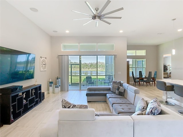 living area with a wealth of natural light, wood finished floors, and a ceiling fan