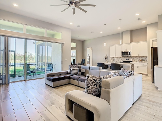 living area with light wood finished floors, recessed lighting, a healthy amount of sunlight, and ceiling fan