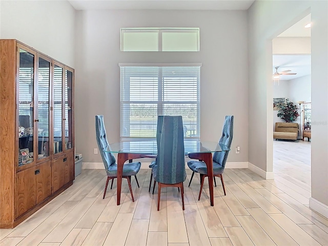 dining space with a ceiling fan, baseboards, and light wood finished floors