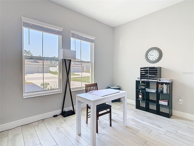 office featuring a healthy amount of sunlight, baseboards, and light wood-type flooring