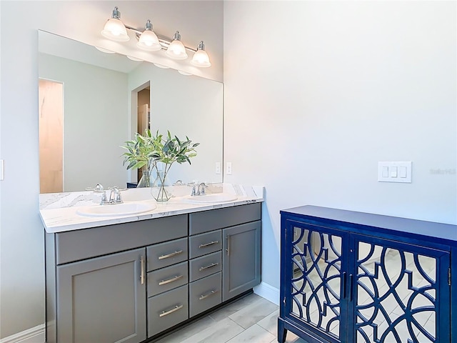 full bathroom featuring a sink, baseboards, and double vanity
