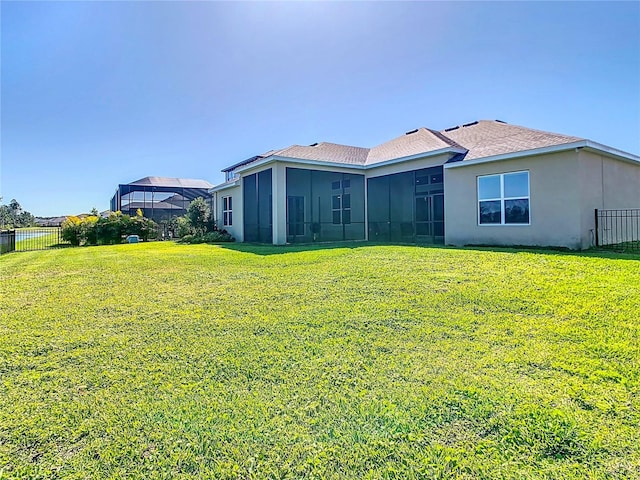 back of property with stucco siding, a shingled roof, a yard, and fence