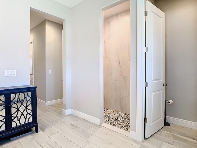full bathroom with tiled shower, baseboards, and wood tiled floor