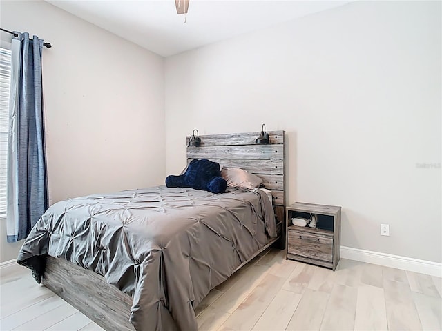 bedroom featuring wood finished floors, baseboards, and ceiling fan
