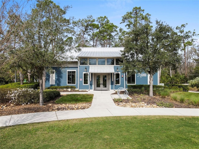 view of front of property featuring a standing seam roof, french doors, metal roof, and a front lawn