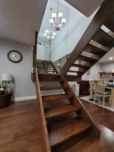 stairway with hardwood / wood-style flooring and an inviting chandelier